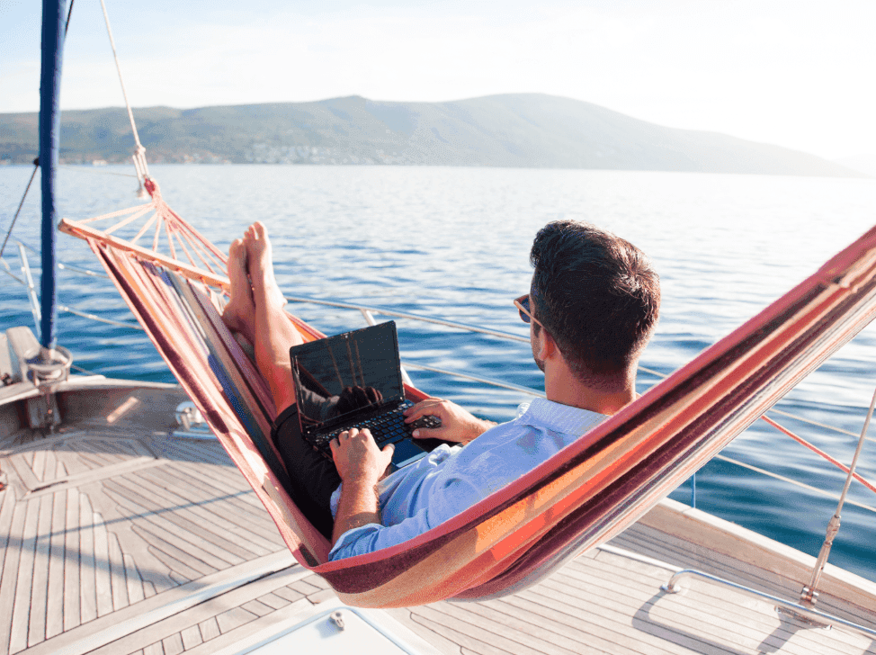 Muž na hamace u moře s počítačem