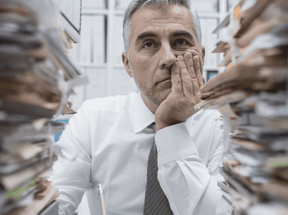 Ztrápený muž se štosy papírů