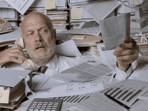 Muž v kanceláři zavalený účtenkami