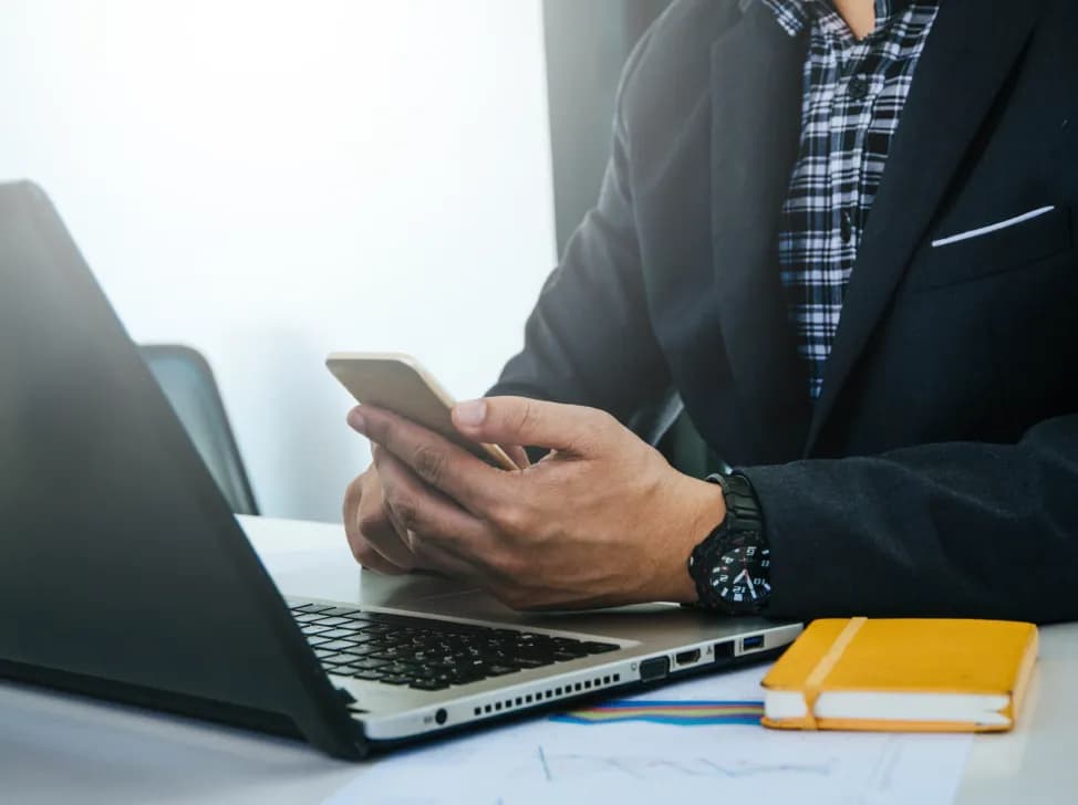 Byznysmen u notebooku s mobilem v ruce