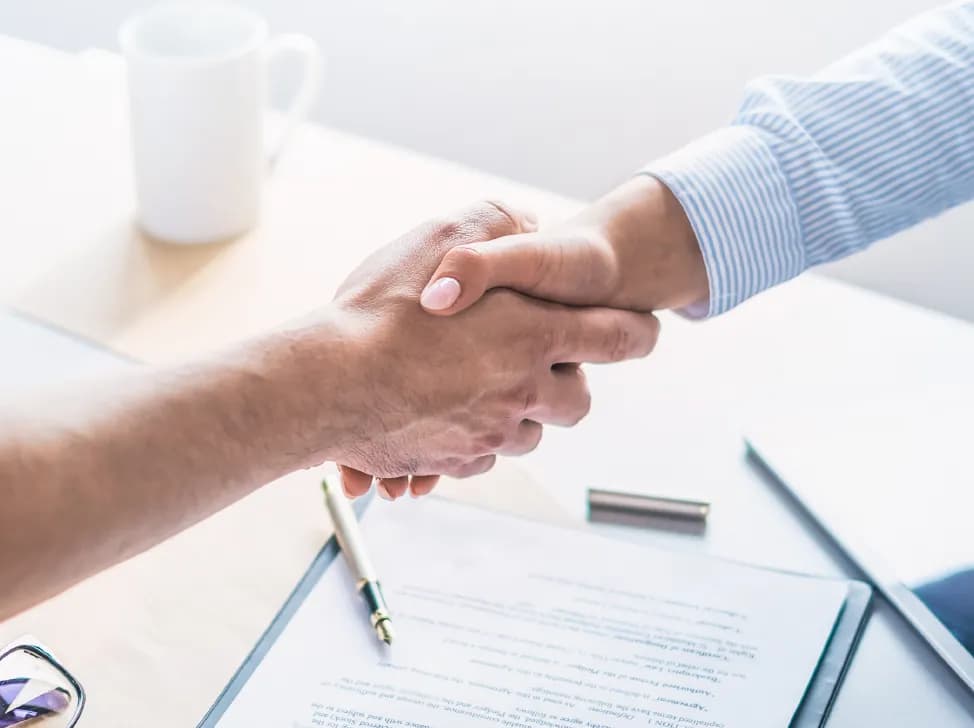 Lidé potřásající si rukama nad dokumenty