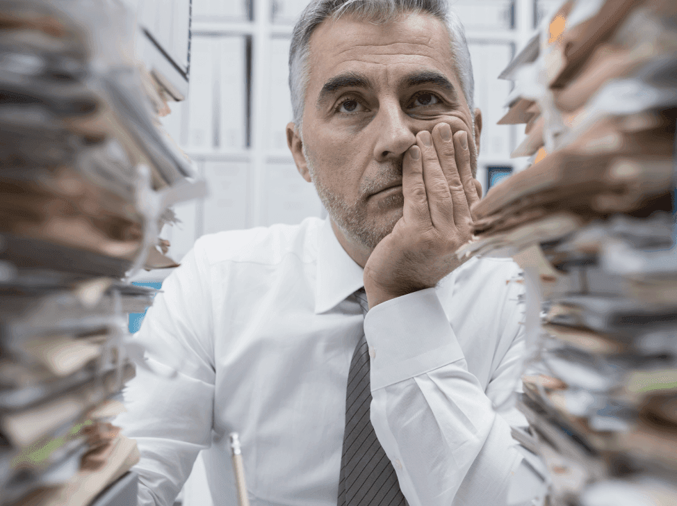 Ztrápený muž se štosy papírů