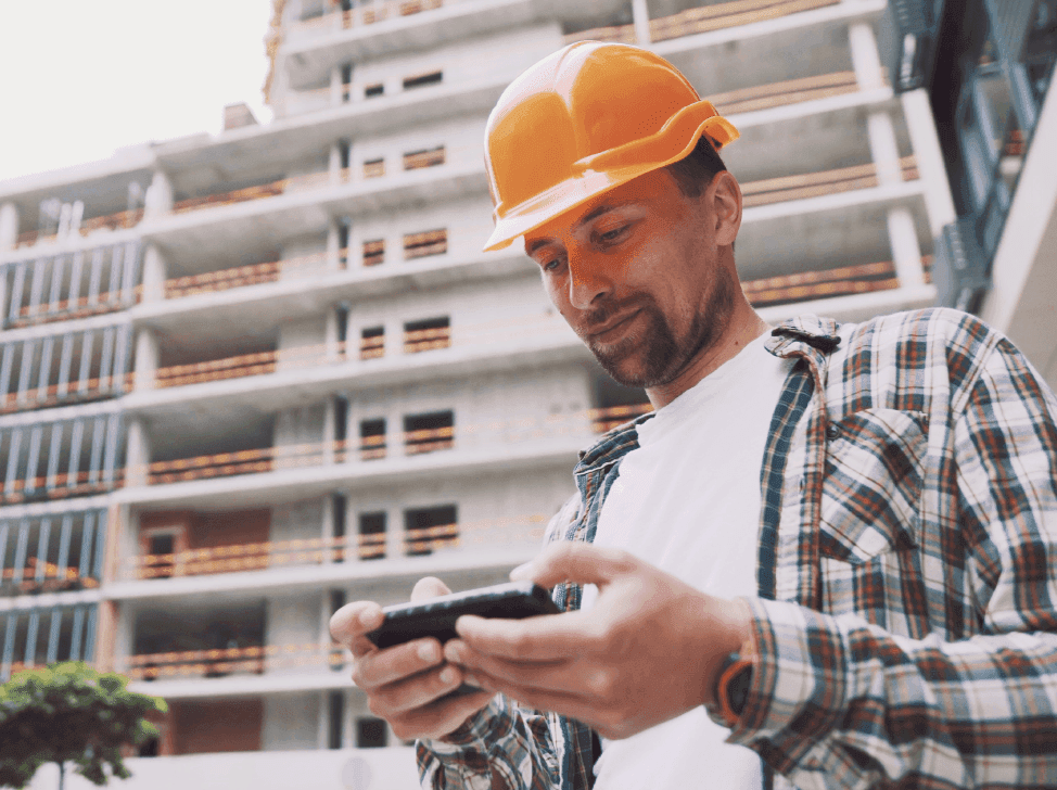 Muž na stavbě kontroluje finance v mobilu