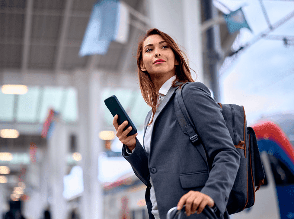 Byznys žena se zavazadlem a mobilem v ruce na letišti