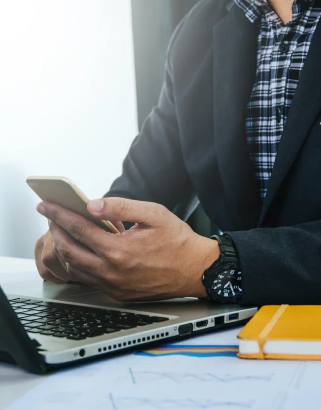 Byznysmen u notebooku s mobilem v ruce