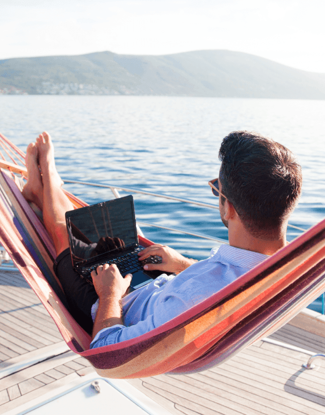 Muž na hamace u moře s počítačem
