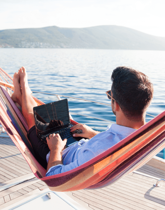 Muž na hamace u moře s počítačem