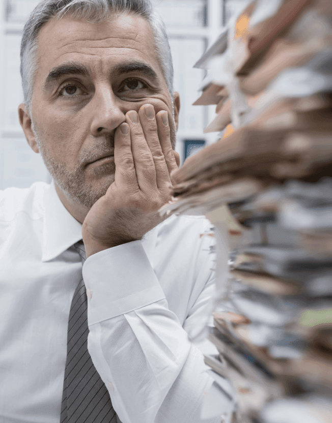 Přehlcený člověk se štosy papírů