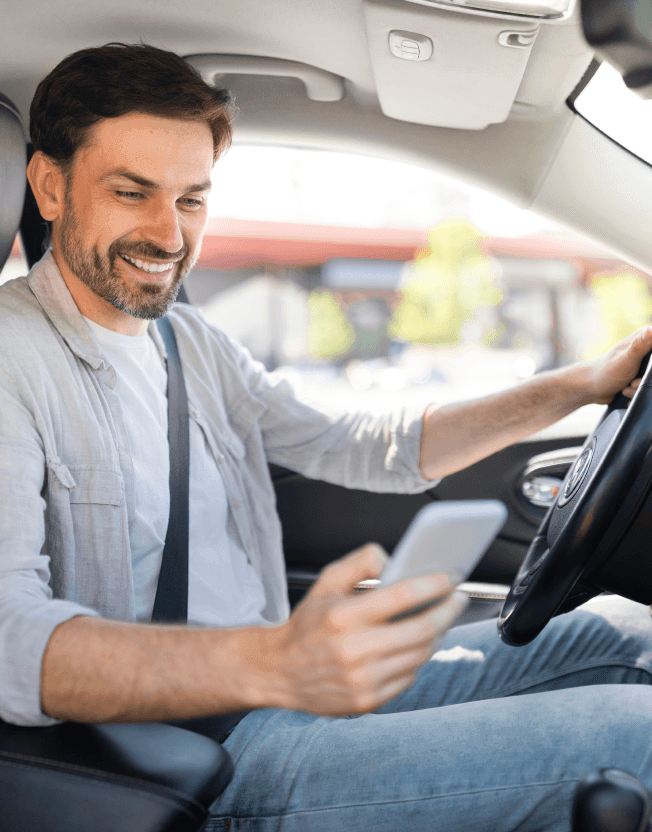 Muž kontroluje cestovní příkaz v mobilu v autě