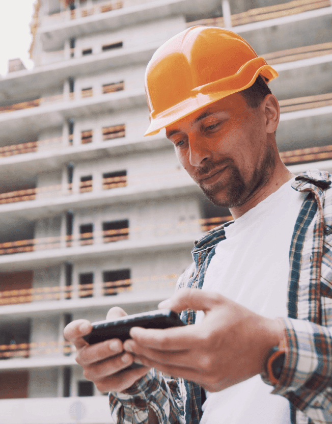 Muž na stavbě kontroluje finance v mobilu