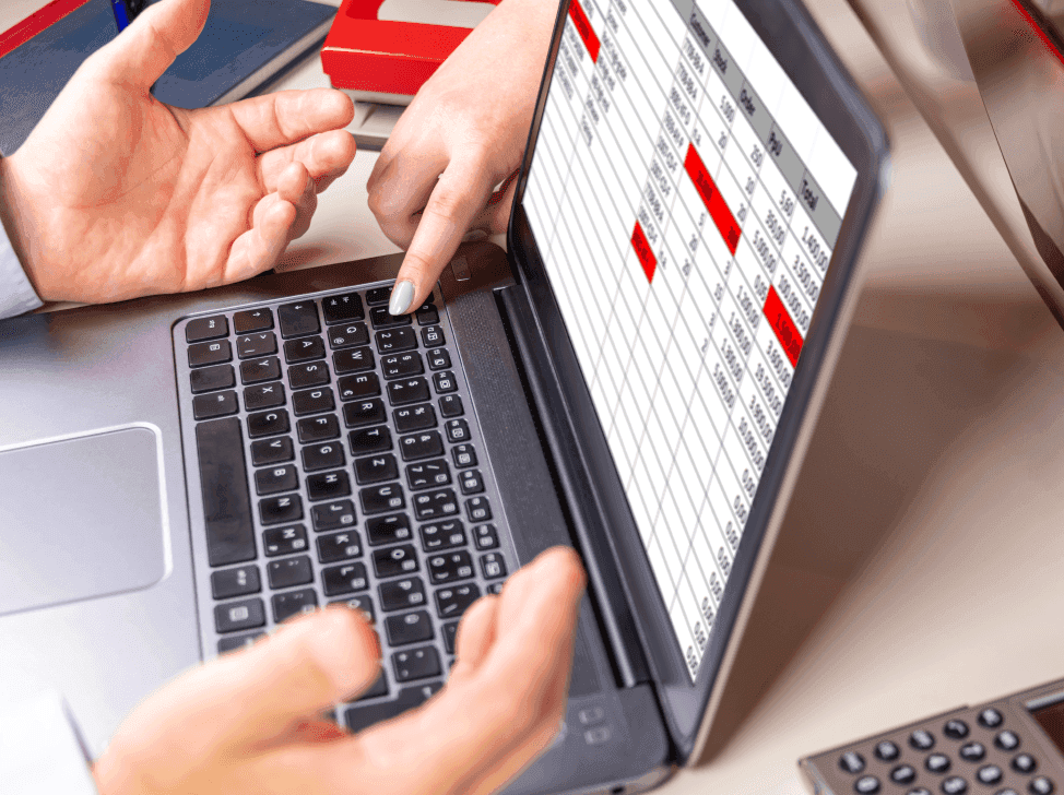 Muž rozhazující ruce nad tabulkami v notebooku