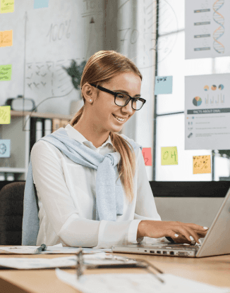 Mladá slečna s brýlemi pracuje na notebooku u stolu v kanceláři